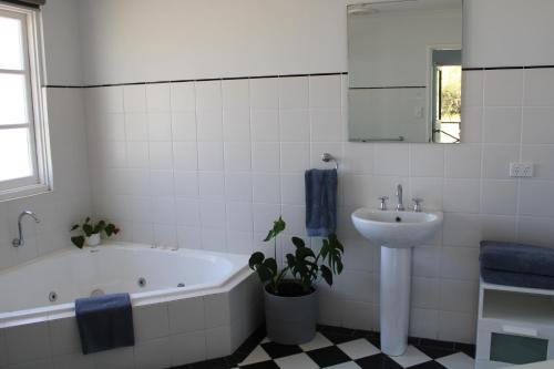 a white bathroom with a tub and a sink at Upper Reach Spa Cottage in Henley Brook