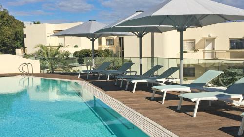 a pool with chairs and umbrellas next to a building at Hapimag Apartments Antibes in Antibes