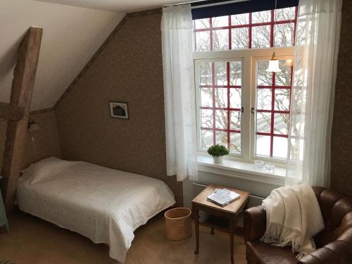 um quarto com uma cama, uma cadeira e uma janela em Medstugans vandrarhem em Duved