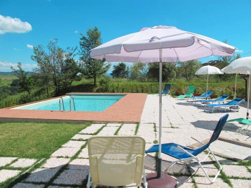 eine Gruppe Stühle und ein Sonnenschirm neben einem Pool in der Unterkunft Holiday Home Villa Caggio-4 by Interhome in Volterra