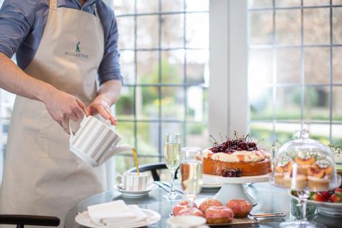 a man in an apron is preparing a cake at Hogarths in Solihull