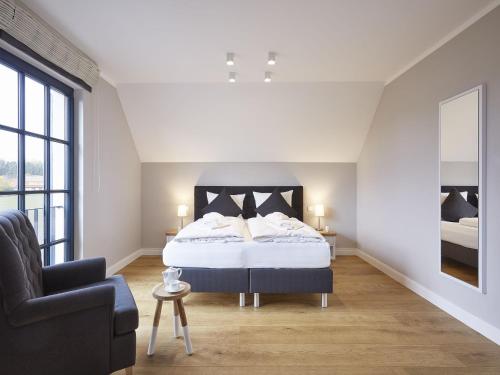 a white bedroom with a bed and a chair at Reetland am Meer - Superior Reetdachvilla mit 2 Schlafzimmern und Kamin F06 in Dranske