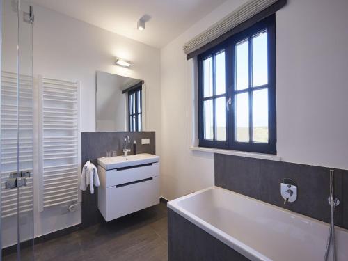 a bathroom with a tub and a sink and a mirror at Reetland am Meer - Superior Reetdachvilla mit 2 Schlafzimmern und Kamin F06 in Dranske