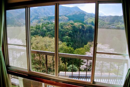 a window with a view of a river and mountains at Takachiho B&B Ukigumo in Takachiho