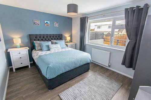 - une chambre bleue avec un lit et une fenêtre dans l'établissement Sandbanks Braunton, Stylish Cottage near to Saunton Beach Sleeps 4, à Croyde