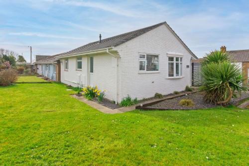 a small white house with a green yard at Sandbanks Braunton, Stylish Cottage near to Saunton Beach Sleeps 4 in Croyde