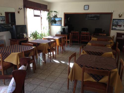 a dining room with tables and chairs and a tv at Hosteria Laura in San Martín de los Andes