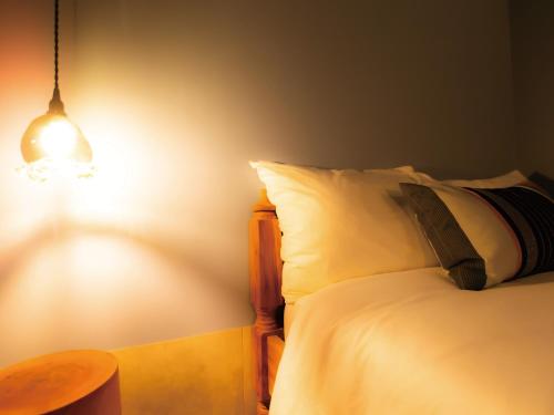 a bedroom with a bed with a lamp and a table at CHULAX OKINAWA YOMITAN【Designer Condominium Hotel】 in Yomitan