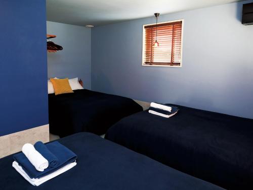 two beds in a room with blue walls and a window at CHULAX OKINAWA YOMITAN【Designer Condominium Hotel】 in Yomitan