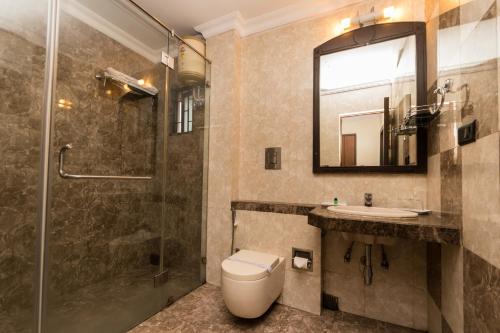 a bathroom with a shower and a toilet and a sink at The Mark Hotel in Kolkata
