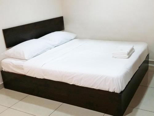 a bed with a black frame and white sheets at Old Penang Hotel - Ampang Point in Ampang
