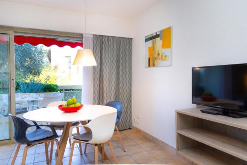 a living room with a table with chairs and a television at Hapimag Apartments Antibes in Antibes