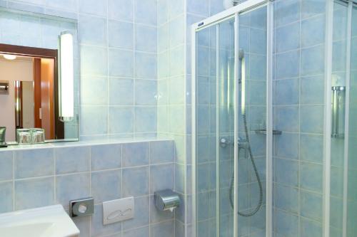 a blue tiled bathroom with a shower and a sink at Hapimag Apartments Antibes in Antibes