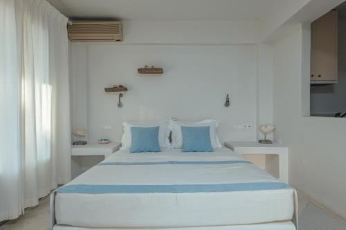 a white bedroom with a large bed with blue pillows at Terra in Parikia