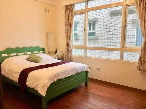 a bedroom with a green bed and a large window at CountrySide B&B in Zhuangwei