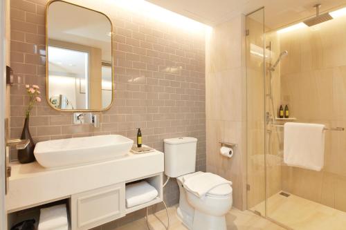 a bathroom with a sink and a toilet and a mirror at The Quarter Ploenchit by UHG in Bangkok