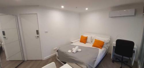 a bedroom with a bed with orange and white pillows at Cozy Studio in heart of the City in Canberra