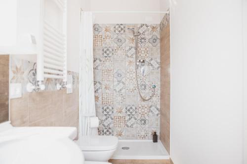 y baño con aseo y ducha con pared de azulejos. en Agriturismo Il Capitolo, en Carpaneto Piacentino