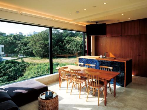 une salle à manger avec une table, des chaises et une grande fenêtre dans l'établissement CHULAX OKINAWA YOMITAN【Designer Condominium Hotel】, à Yomitan