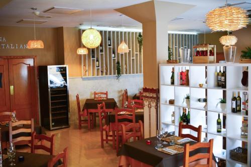 a restaurant with tables and chairs and a shelf of wine bottles at Hotel L'Escala in Cullera