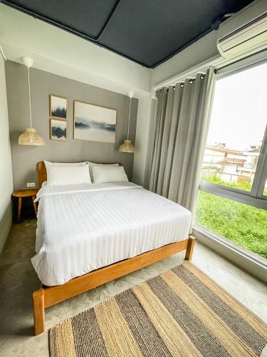 a bedroom with a bed and a large window at Bedgasm Hostel Chanthaburi in Chanthaburi