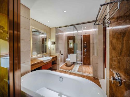 a bathroom with a tub and a toilet and a sink at Marco Polo Jin Jiang in Jinjiang