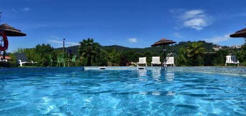 a large swimming pool with chairs and umbrellas at Quinta Lama de Cima in Fafe
