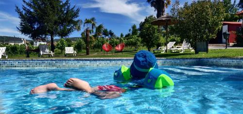 a young boy laying on an inner tube in a swimming pool at Quinta Lama de Cima in Fafe