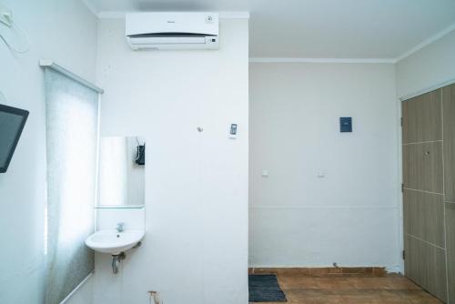 a white bathroom with a sink and a mirror at 77 Guest House Serpong Mitra RedDoorz in Jakarta