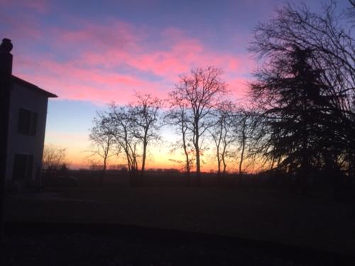 a sunset with a group of trees and a house at Agriturismo Il Capitolo in Carpaneto Piacentino