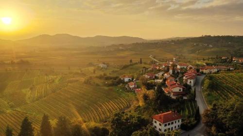a village on a hill with the sun setting in the background at Dvor Vipolže in Dobrovo