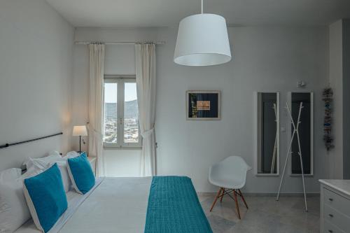 a white bedroom with a blue bed and a window at Terra in Parikia