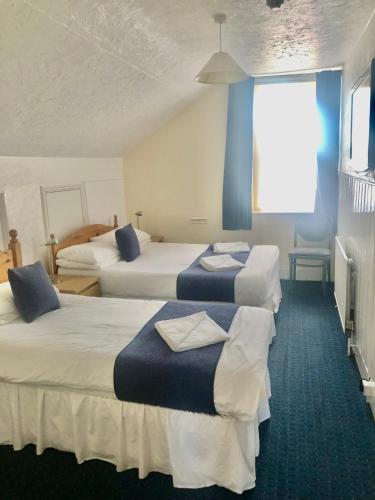a hotel room with three beds and a window at The Grosvenor in Clacton-on-Sea