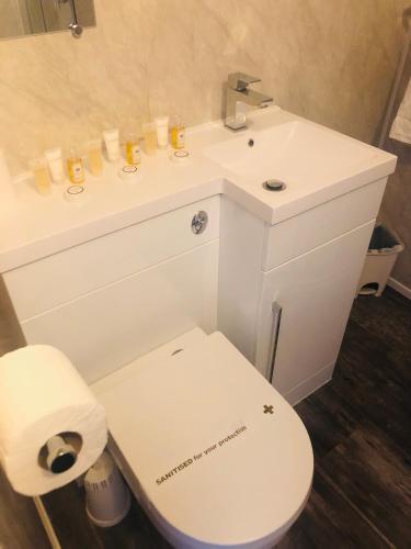 a white bathroom with a toilet and a sink at The Grosvenor in Clacton-on-Sea