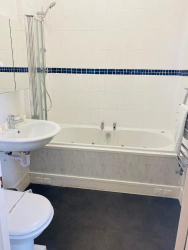 a bathroom with a tub and a sink and a toilet at The Grosvenor in Clacton-on-Sea