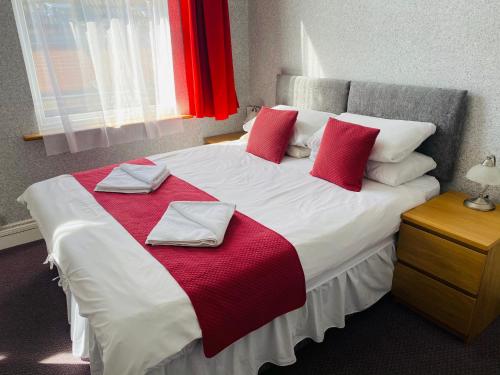 a bedroom with a large bed with red and white pillows at The Grosvenor in Clacton-on-Sea