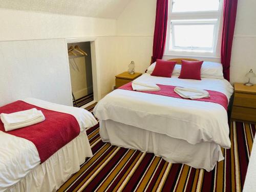 a bedroom with two beds with red and white sheets at The Grosvenor in Clacton-on-Sea