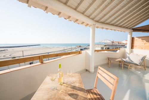 a table with a bottle of wine on a balcony with the beach at Hôtel Casa Marina in Saintes-Maries-de-la-Mer