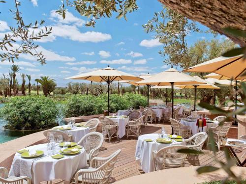 a restaurant with white tables and chairs and umbrellas at Fairmont Royal Palm Marrakech in Marrakech
