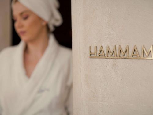 a woman in a white robe and hat next to a sign at Fairmont Royal Palm Marrakech in Marrakech