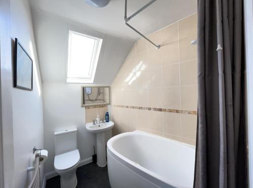a bathroom with a tub and a toilet and a sink at One-Bedroom flat in Cheam Village in Cheam
