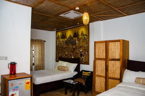 a bedroom with two beds and a painting on the wall at Ike's Cultural Village in Kumasi