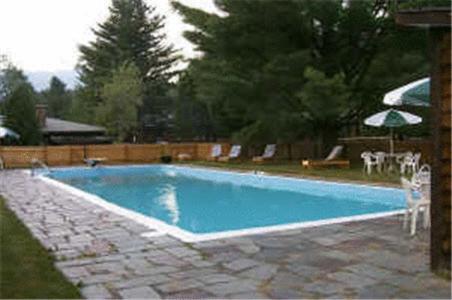 a large blue swimming pool with chairs and an umbrella at Northern Lights Lodge in Stowe