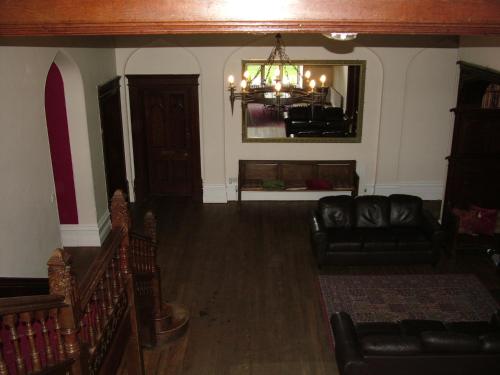 a living room with black leather furniture and a chandelier at Hargate Hall Self Catering in Buxton