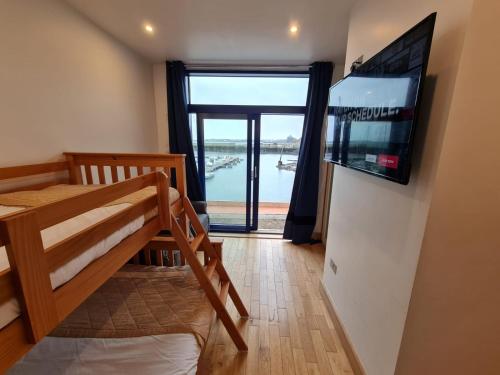カーリングフォードにあるCarlingford Marina Apartmentsの二段ベッド1台、薄型テレビが備わる客室です。