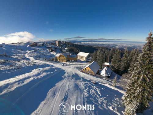 Une montagne enneigée avec une ville au sommet dans l'établissement Montis Hotel & Spa, à Muntele Mic