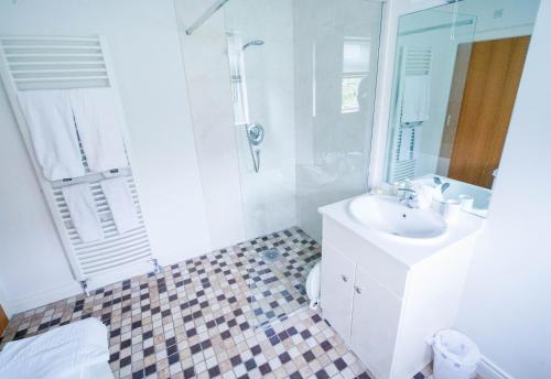 a white bathroom with a sink and a shower at Glenburn Galgorm Bed & Breakfast in Galgorm