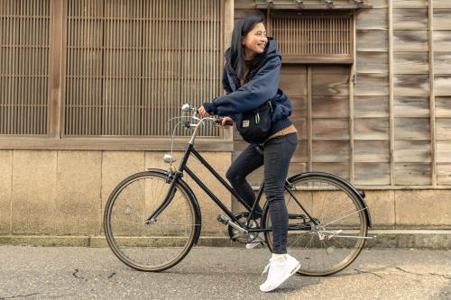 a woman riding a bike while talking on a cell phone at LINNAS Kanazawa in Kanazawa