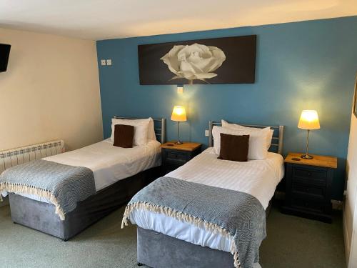 two beds in a room with blue walls at The Fountain Hotel in Hawes