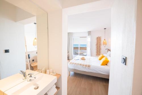 a bedroom with a bed and a bathroom with a mirror at Hôtel Casa Marina in Saintes-Maries-de-la-Mer